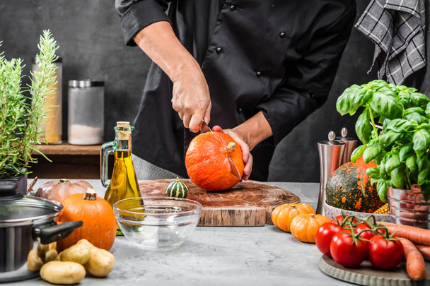 cropped shot of male chef cutting pumpkin in kitchen  - Фото, изображение