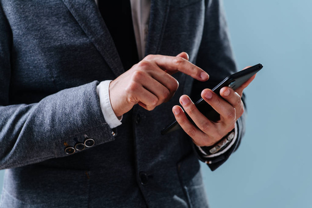 Empresário está selecionando um aplicativo seu smartphone sobre fundo azul
 - Foto, Imagem