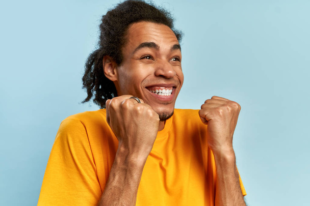 I won. Winning success happy man celebrating being a winner. Dynamic image of African-American male model on blue studio wall. Victory, delight concept. Human facial emotions concept. Trendy colors. - Фото, зображення
