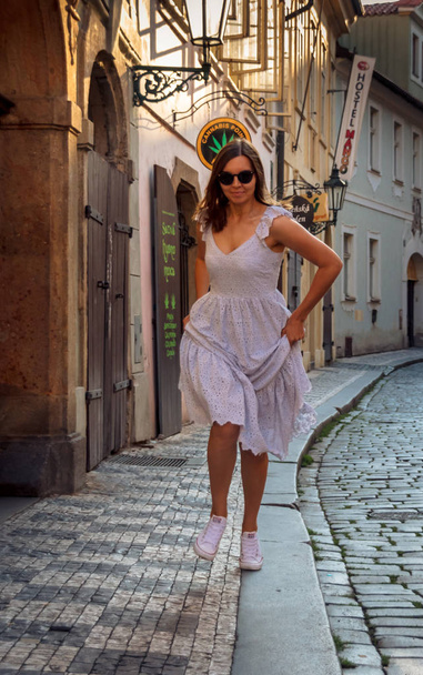Ένα κορίτσι περπατά στην Πράγα μια ηλιόλουστη μέρα. - Φωτογραφία, εικόνα