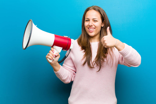 young woman with a megaphone against blue background - Photo, image