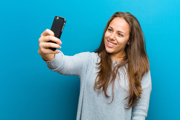 νεαρή γυναίκα με ένα κινητό τηλέφωνο σε μπλε φόντο - Φωτογραφία, εικόνα