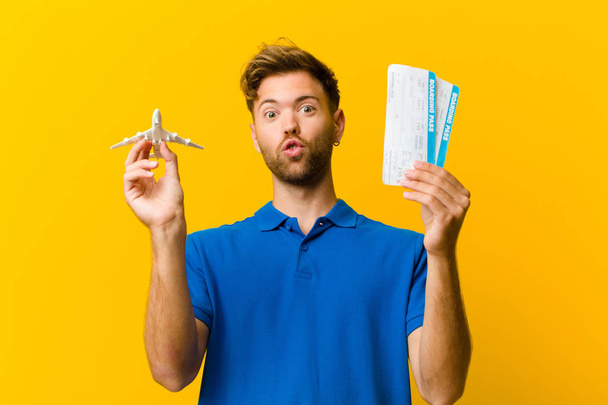 young man with boarding pass tickets against orange background - Foto, Imagem