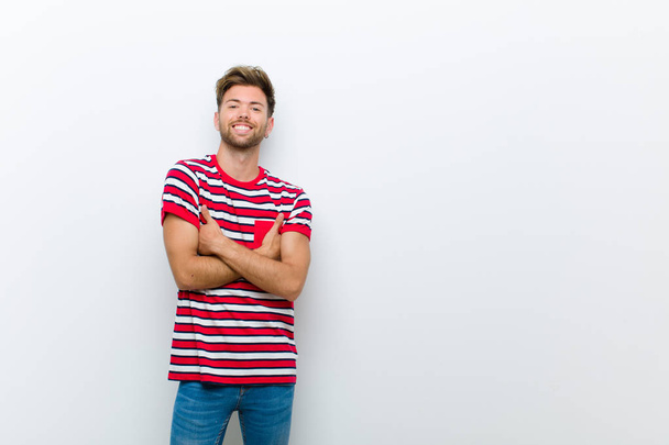 young man laughing happily with arms crossed, with a relaxed, positive and satisfied pose against white background - Foto, imagen
