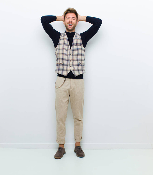 young full body man looking happy, carefree, friendly and relaxed enjoying life and success, with a positive attitude against white background - 写真・画像