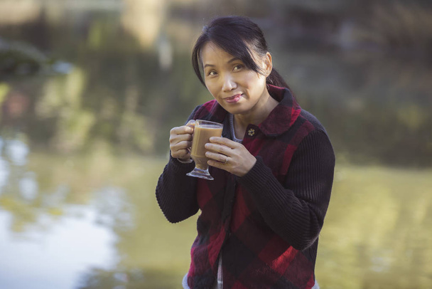 Жінка насолоджується чашкою кави біля води
. - Фото, зображення