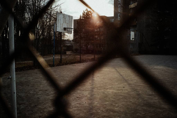 Campo de basquete em um quintal tiro através de cerca ao pôr do sol
 - Foto, Imagem