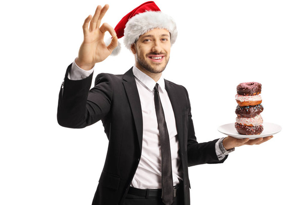 Homme d'affaires avec une assiette de beignets portant un chapeau du Père Noël et
 - Photo, image
