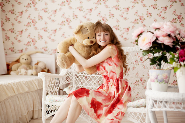 Woman holding a toy bear in a nursery - Φωτογραφία, εικόνα