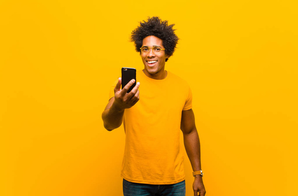 young african american man with a smart phone against orange bac - Foto, immagini