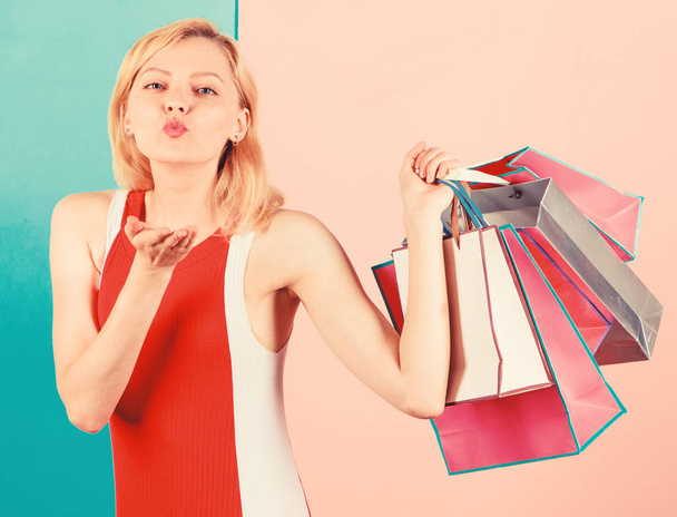 Girl satisfied with shopping. Tips to shop sales successfully. Girl enjoy shopping or just got birthday gifts. Woman red dress hold bunch shopping bags blue pink background. Buy everything you want - Φωτογραφία, εικόνα