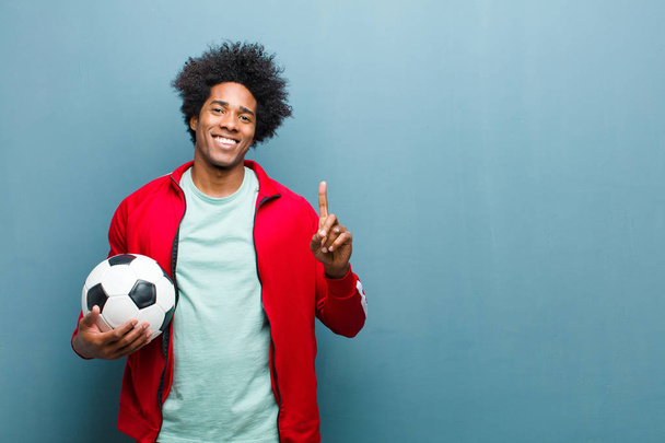 young black sports man with a soccer ball against blue grunge wa - Fotoğraf, Görsel