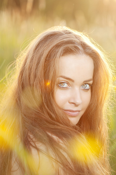 Smiling woman in a field at sunset - Foto, Bild