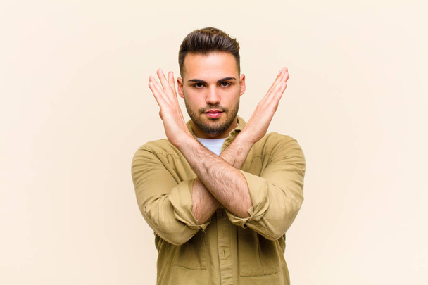 young hispanic man looking annoyed and sick of your attitude, saying enough! hands crossed up front, telling you to stop against isolated background - Fotoğraf, Görsel