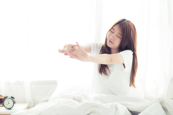 美しい若いアジアの女性がストレッチし、目覚め後にベッドでリラックス  - 写真・画像
