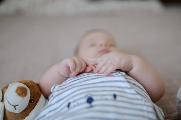 Erkek bebeğin el ele tutuşmasına yakın durun. Bebeğin yanında Teddy var. Ellere seçici odaklanma. - Fotoğraf, Görsel