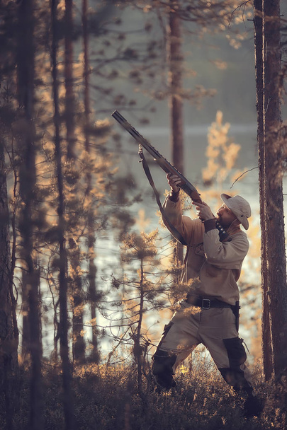 hunting man / hunter with a gun hunting in the autumn forest, yellow trees landscape in the taiga - Fotoğraf, Görsel