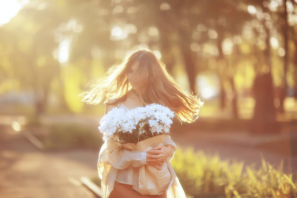chica feliz con flores en la ciudad / foto de verano joven hermosa niña sosteniendo un ramo de flores en una calle de la ciudad
 - Foto, Imagen