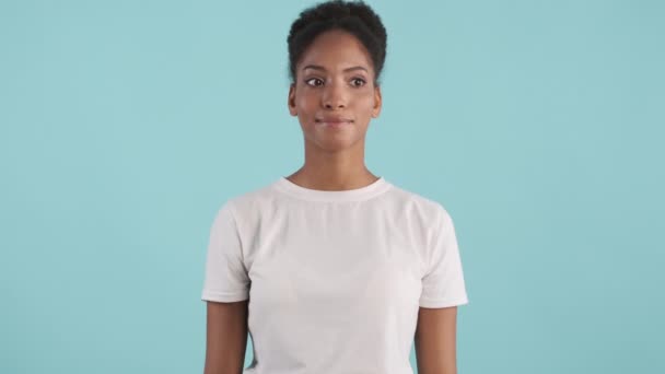 portret van enthousiast Afrikaans amerikaans meisje gelukkig knikken kijkend in camera over blauwe achtergrond - Video
