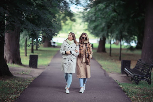 autumn fashion park girls two look / walk in a city park two glamorous fashionable girlfriends in a coat - 写真・画像