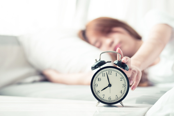 Mooie Aziatische jonge vrouw uitschakelen alarm clock in de ochtend, wak - Foto, afbeelding