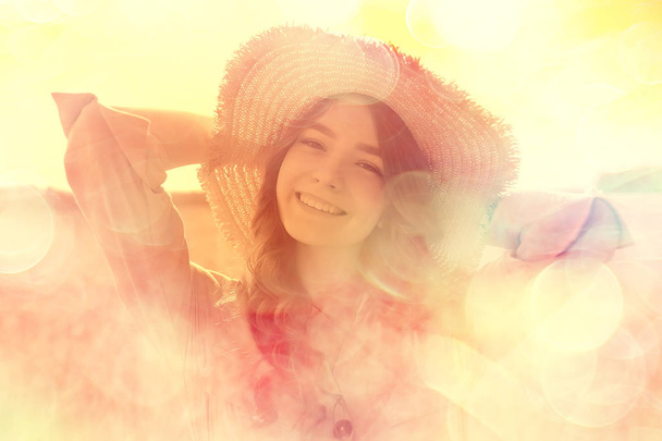 girl sitting in a field with a straw hat / summer vacation, rest young adult happy woman - Foto, afbeelding