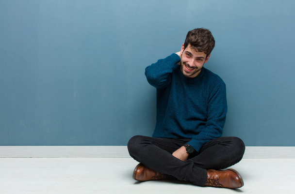 young handsome man sitting on floor laughing cheerfully and confidently with a casual, happy, friendly smile - Foto, Imagen