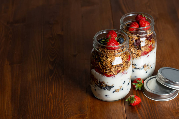 homemade granola with berries in glass jars - Foto, afbeelding