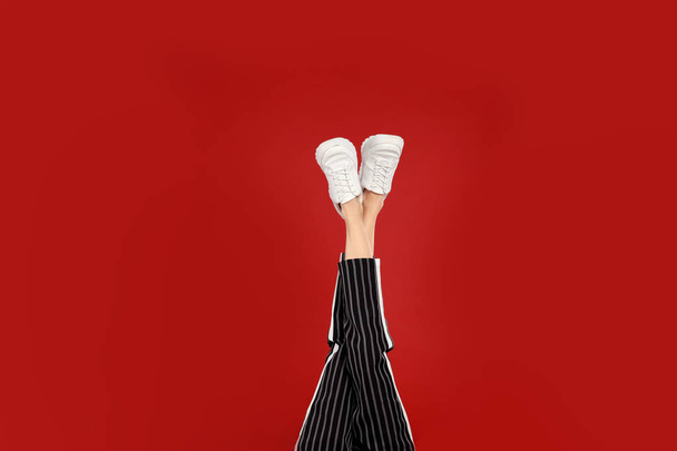 Woman in stylish sport shoes on red background - Fotoğraf, Görsel