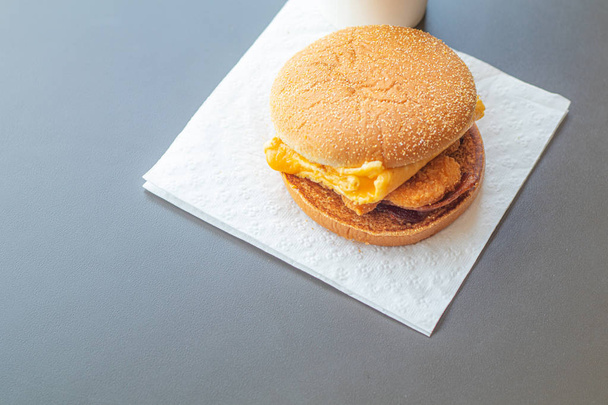 Der Hamburger wurde auf Toilettenpapier gelegt. auf einem grauen Tisch in einem f - Foto, Bild