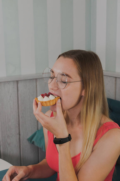 Girl in a cafe eats sweet and fresh desserts. - Fotoğraf, Görsel