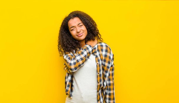 joven mujer afroamericana bonita sentirse cansado, estresado, ansioso, frustrado y deprimido, que sufre con dolor de espalda o cuello contra la pared amarilla
 - Foto, Imagen