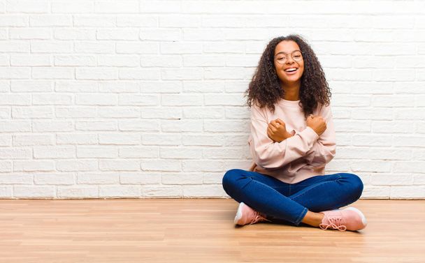 young african american black woman smiling cheerfully and celebrating, with fists clenched and arms crossed, feeling happy and positive - Zdjęcie, obraz
