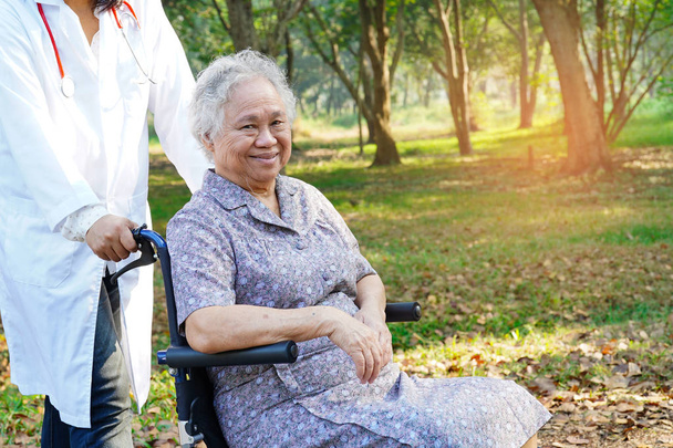 Lääkäri apua ja hoitoa Aasian vanhempi tai vanhusten vanha nainen nainen potilas istuu pyörätuolilla puistossa hoitotyön sairaalassa: terve vahva lääketieteellinen käsite
 - Valokuva, kuva