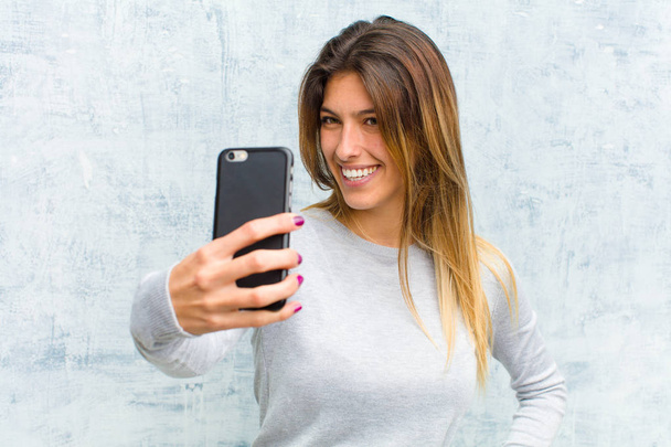 young pretty woman with a smart phone against grunge wall - Фото, зображення