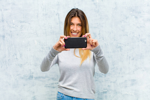 young pretty woman with a smart phone against grunge wall - Foto, Imagem