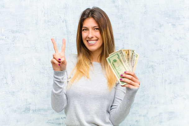 young pretty woman with banknotes against grunge wall - Фото, изображение