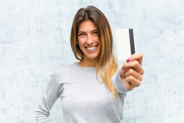 young pretty woman with a credit card against grunge wall - Fotoğraf, Görsel