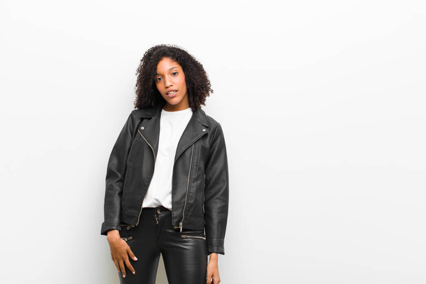 young pretty black woman wearing a leather jacket against white wall - Zdjęcie, obraz