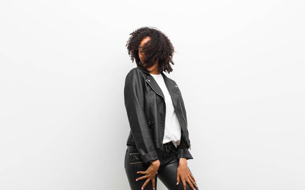 young pretty black woman dancing wearing a leather jacket against white wall - Foto, Imagem