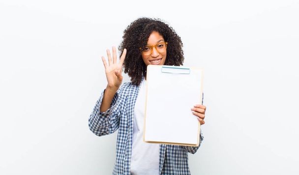young pretty black woman with a sheet of paper against white wall - Fotografie, Obrázek