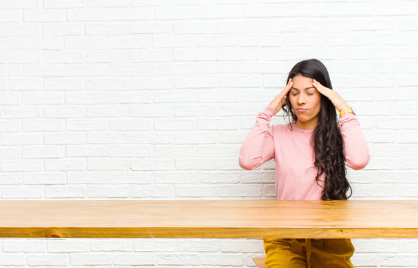 nuori kaunis latino nainen, joka näyttää stressaantuneelta ja turhautuneelta, työskentelee paineen alaisena päänsärkyä ja vaivaa pöydän edessä istuvia ongelmia
 - Valokuva, kuva