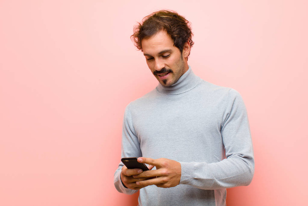 young handsome man with a smart phone against pink flat wall - Foto, immagini