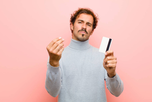 young handsome man with a credit card against pink flat wall - Φωτογραφία, εικόνα