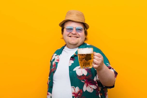 young big size man with a pint of beer against flat wall - Foto, imagen