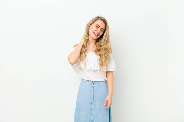 young blonde woman laughing cheerfully and confidently with a casual, happy, friendly smile against white wall - Photo, Image