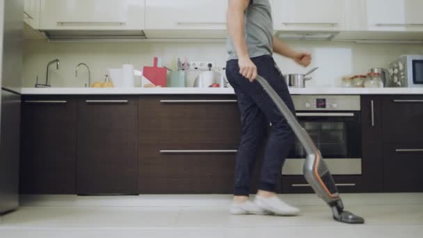Χαρούμενος άνθρωπος καθαρισμός πάτωμα κάνει ζιγκ ζαγκ κινήσεις με ηλεκτρική σκούπα. - Πλάνα, βίντεο