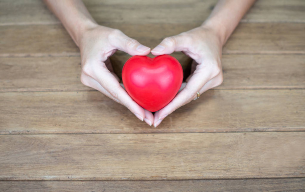Hand holding heart shape on wooden background - Photo, Image