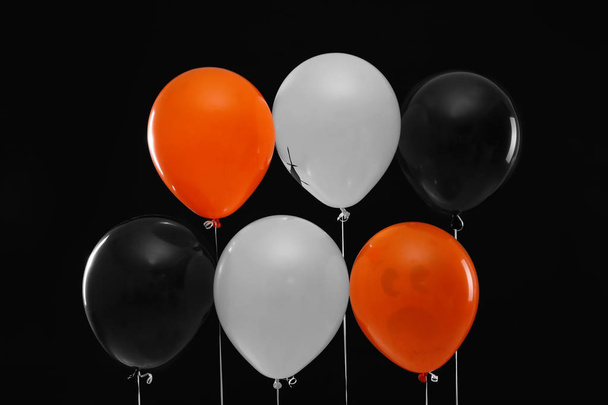 Color balloons for Halloween party on black background - 写真・画像