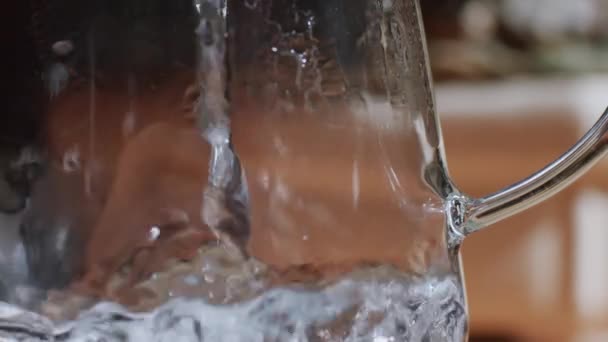 Close up shot of water falling into glass kettle with bright bubbles slow motion. Clear transparent jar with boiling aqua macro motion wallpaper. Healthy lifestyle essentials necessity natural energy  - Footage, Video